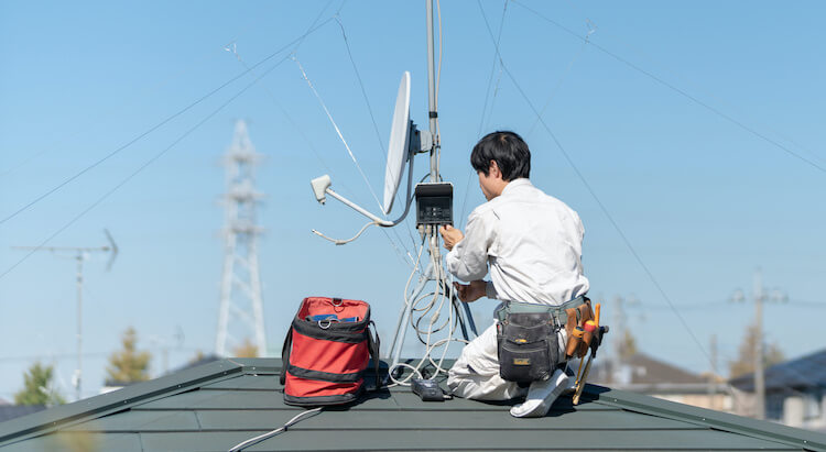 屋根上の八木式アンテナを調整する作業員